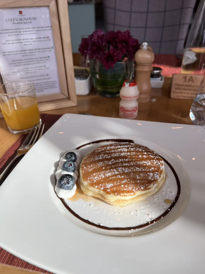 ブルーベリーを添えたパンケーキとオレンジジュース、ヤクルトが並ぶ朝食